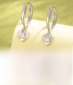 Détail macro de boucles d'oreilles créoles cœur en cuivre argenté et zircone clair