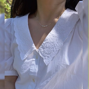 White short sleeve cotton shirt with V-neckline and delicate floral embroidery details