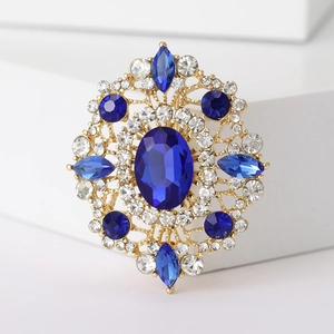 Macro shot of oval blue crystal brooch with vintage gold setting and sparkling clear gems