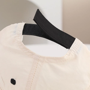 Detail of adjustable black velcro strap on the back of a beige toddler baseball cap