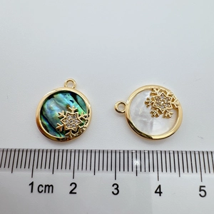 Macro detail of 18K gold-plated snowflake charms with abalone and mother of pearl