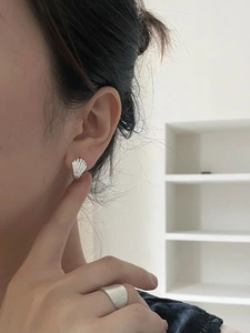 Close-up of minimalist shell heart earrings in silver on model with indoor background