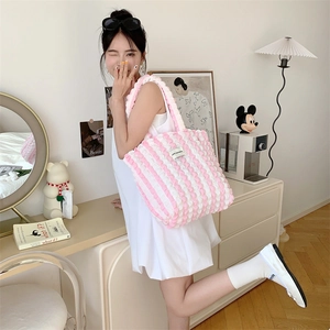 Close-up of pink and white striped bubble texture tote bag on a model in home setting