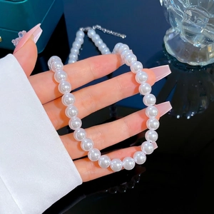 Macro detail of white pearl necklace with adjustable silver lobster clasp and chain