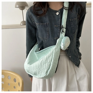 Detail of mint green pleated canvas crossbody bag with small round coin purse attachment