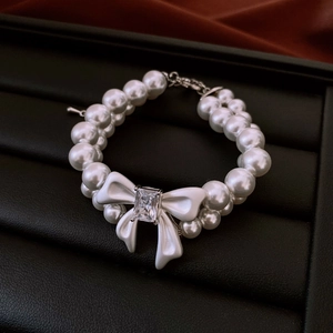 Detailed close-up of double-layer pearl bracelet with bow and zircon on velvet tray