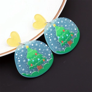 Détail de boucles d'oreilles sapin de Noël en acrylique bleu sur plateau en céramique