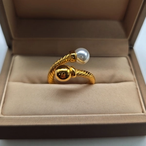 Detail of twisted cable ring with a white pearl and gold bead in a beige jewelry box
