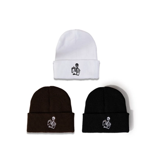 Trois bonnets en maille blanc, marron et noir avec broderie squelette buvant du thé