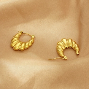 Gros plan de boucles d'oreilles croissant dorées en U sur fond de soie champagne élégant
