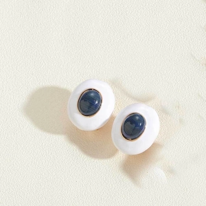 Macro view of French vintage oval stud earrings with blue gemstone and white enamel finish