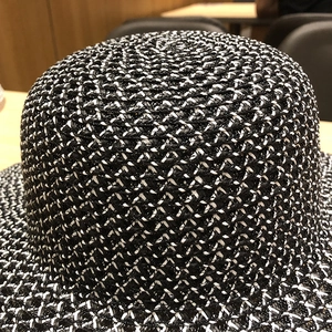 Gros plan sur la texture tissée et le motif noir et blanc de ce chapeau d'été en paille