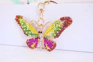 Close-up of golden butterfly keychain with vibrant yellow green and purple crystals