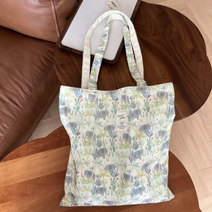 Detailed view of canvas tote bag with elephant floral print on a rustic wood table