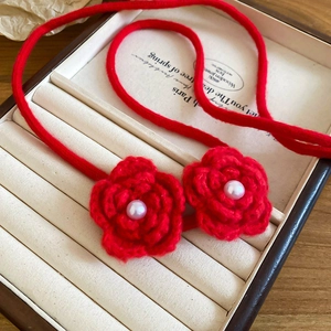 Macro detail of red knitted rose pendant necklace with pearls in a luxury jewelry box
