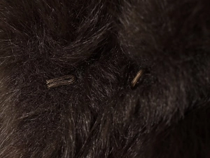Gros plan sur la texture de fourrure synthétique marron foncé et le crochet tissé du manteau