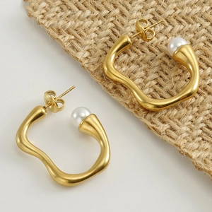 Boucles d'oreilles irrégulières en acier doré avec perles blanches sur toile de lin