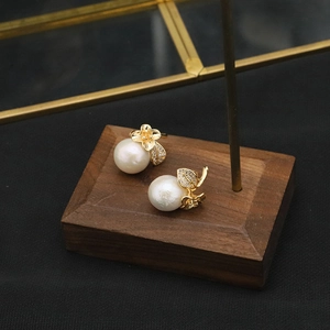 Detail of white freshwater pearl earrings with gold flower and cubic zirconia accents