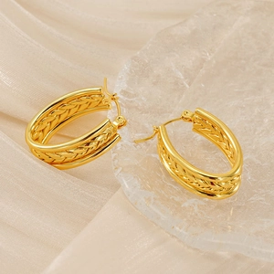 Detailed view of gold twisted hoop earrings on soft silk fabric with elegant lighting
