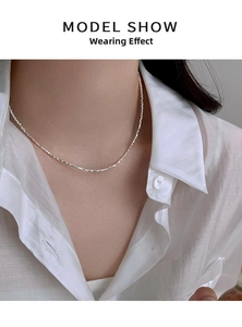 Close-up of minimalist silver clavicle chain worn with a white shirt showing fine details