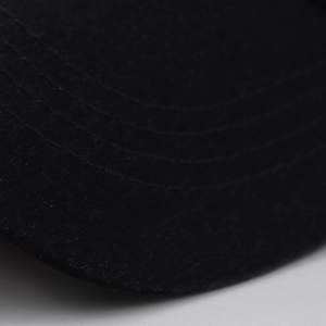 Dettaglio della visiera di un cappello nero con quattro file di cuciture parallele