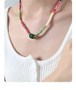 Close-up of handmade necklace with colorful natural stone beads and green agate pendant