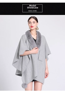 Detail of light gray knit poncho featuring faux rabbit fur collar and playful pom-pom hem