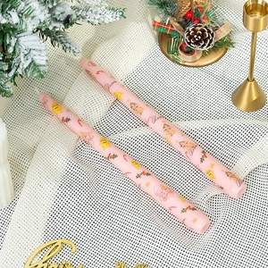 Détail de deux bougies de Noël roses avec motifs de pain d'épices sur tissu en maille
