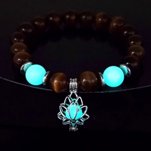 Luminous blue beads and silver lotus charm on a yoga bracelet glowing in the dark