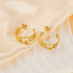 Detailed close-up of 18K gold chain earrings with cutout star and moon charms on silk