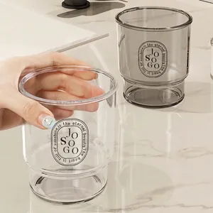 Minimalist thick transparent and smoke grey mouthwash cups on marble counter