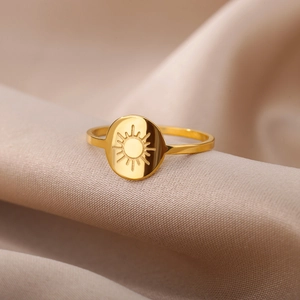 Macro shot of 18K gold stainless steel ring featuring an engraved sun pattern on silk