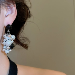 Detail of beaded cluster tassel earrings with pearls and black accents on a female model