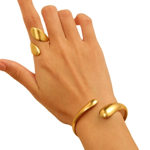 Set di gioielli dorati con anello a goccia e bracciale rigido indossati da una modella
