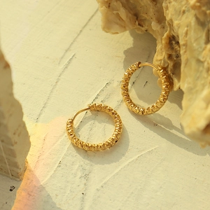 Textured 18K gold plated hoop earrings with vintage hammered finish on stone background