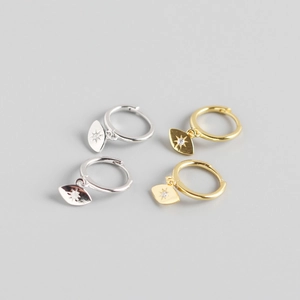 Detailed view of sunburst evil eye hoop earrings in gold and silver finish with crystals
