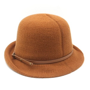 Détail macro du chapeau cloche en tricot caramel avec texture fine et lanière en cuir à clous