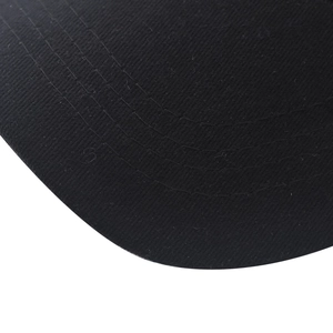 Detailed macro view of black cotton baseball cap brim featuring reinforced stitching lines