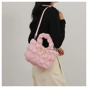 Detail of pink quilted nylon handbag featuring a gold bow and 3D heart pattern embroidery