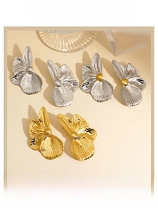 Gros plan de boucles d'oreilles fleurs en acier 316 avec texture métallique brossée
