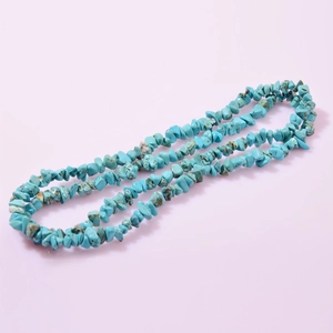 Natural turquoise irregular chip beads for DIY jewelry necklaces on soft pink backdrop