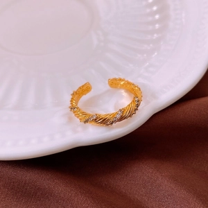 Close-up of 18K gold plated bow ring featuring zircon inlay on a white porcelain dish