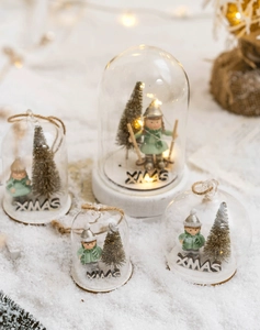 Detailed view of four glass dome Christmas ornaments with glowing LED lights on snow