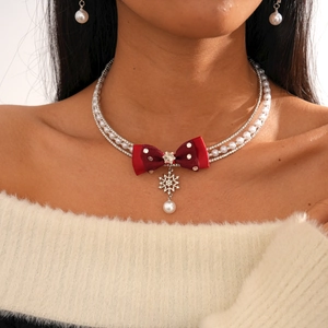 Detail of multi-layer pearl necklace with red bow and rhinestone snowflake charm