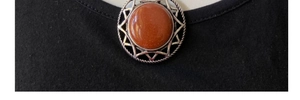 Macro shot of silver hexagram pendant featuring brown sunstone on a black t-shirt