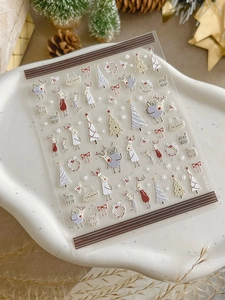 Detail of Christmas nail art stickers with reindeer and tree patterns on ceramic tray