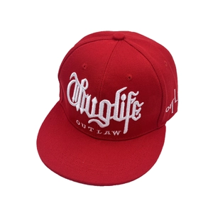 Détail de la broderie Thug Life blanche sur une casquette hip-hop rouge à visière plate