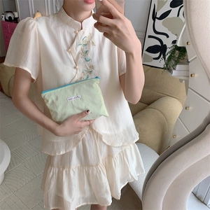 Detail of cream white Chinese style embroidered top with pearl buttons and layered ruffle skirt