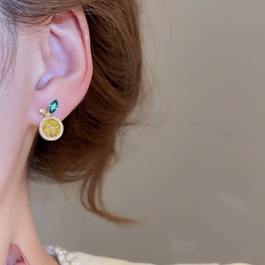 Detail of a lemon slice earring featuring sparkling yellow gems and a green leaf gem