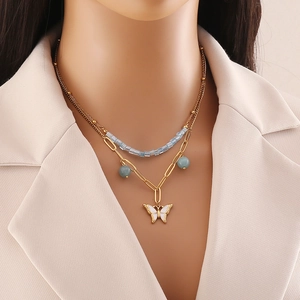 Double-layered gold necklace with light blue beads and a white butterfly pendant